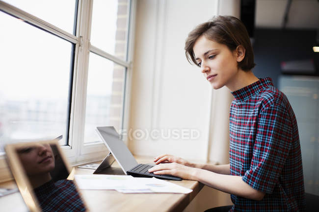 Geschäftsfrau arbeitet an digitalem Tablet im Bürofenster — Stockfoto
