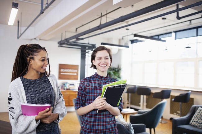 Smiling businesswomen walking and talking in office — Stock Photo