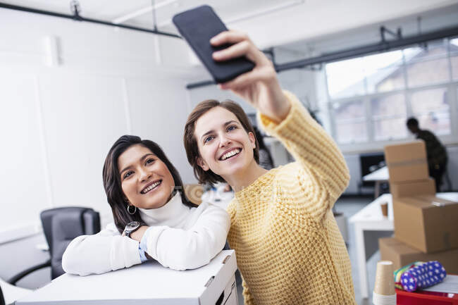 Sorridente donne d'affari prendendo selfie nel nuovo ufficio — Foto stock