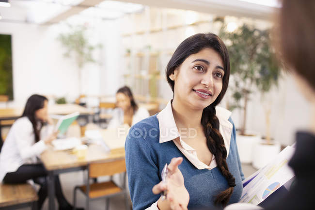 Mujeres de negocios que hablan con su colega en el cargo - foto de stock