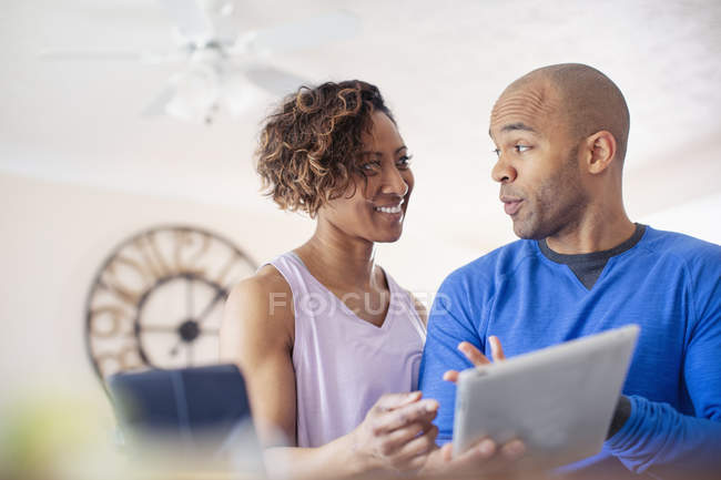 Pareja hablando, usando tableta digital en casa - foto de stock