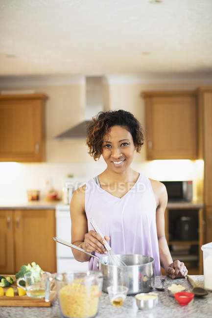 Porträt einer lächelnden, selbstbewussten Frau, die in der Küche kocht — Stockfoto