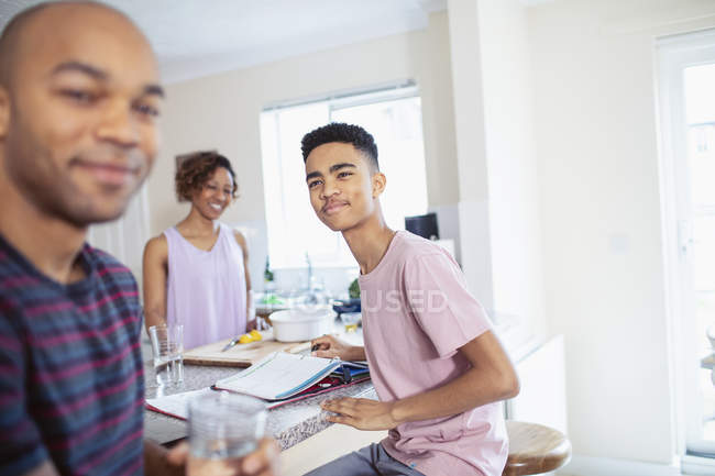 Family cooking and doing homework in kitchen — Stock Photo
