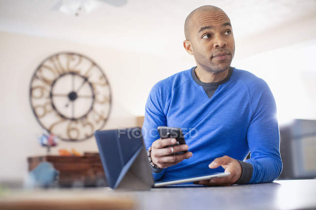 Uomo che utilizza tablet e smartphone digitali a casa — Foto stock