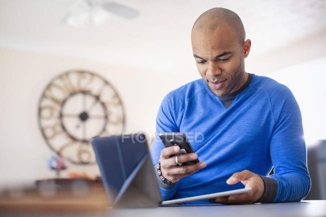 Hombre usando tabletas digitales y teléfonos inteligentes en casa - foto de stock