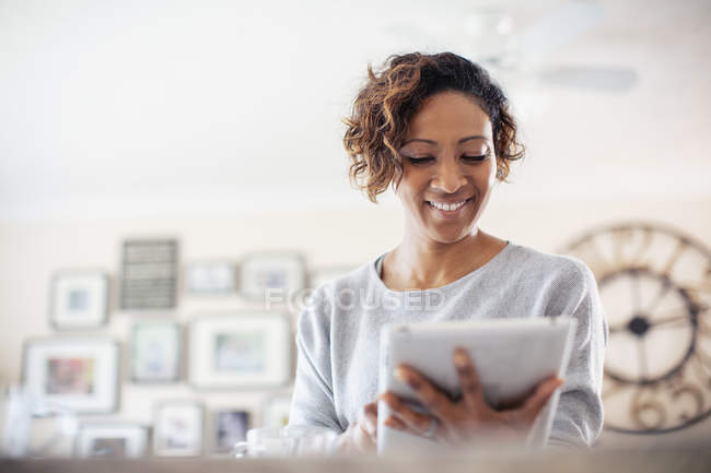 Mulher sorridente usando tablet digital em casa — Fotografia de Stock