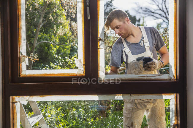 Male painter painting home exterior window trim — Stock Photo