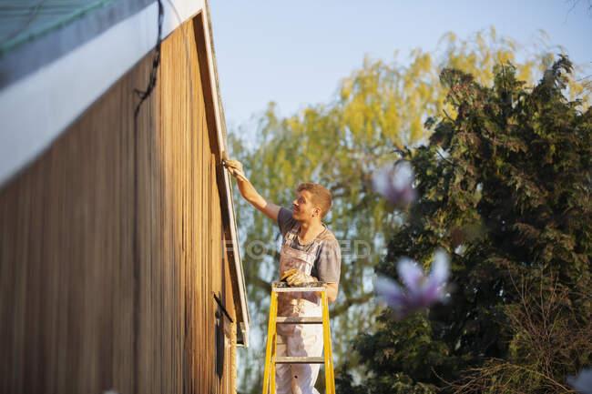 Pintor masculino na escada pintura casa exterior guarnição — Fotografia de Stock