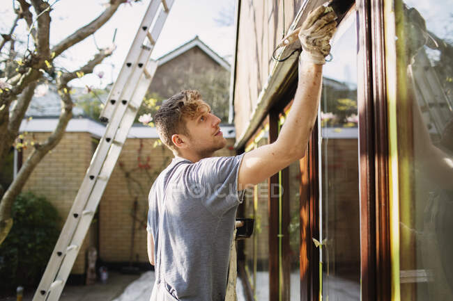 Male painter painting home exterior window trim — Stock Photo