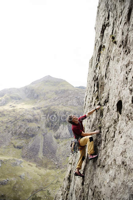 Masculino escalador de rocha escalar rosto de rocha, olhando para cima — Fotografia de Stock