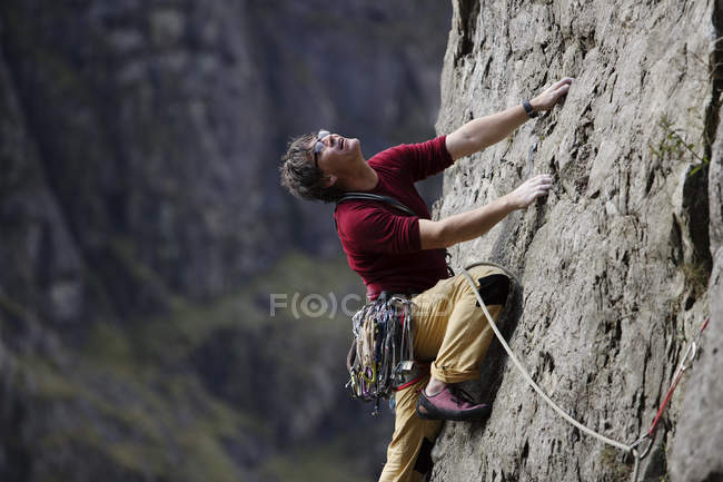 Скалолаз, взбирающийся на скалу, смотрит вверх — стоковое фото