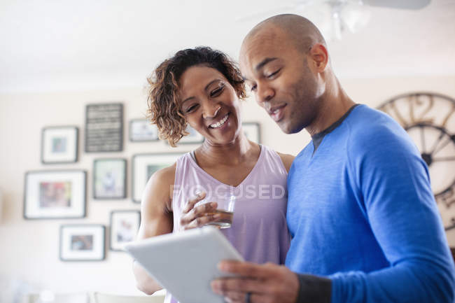 Couple heureux en utilisant une tablette numérique à la maison — Photo de stock