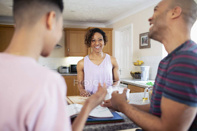 Família feliz fazendo lição de casa e cozinhar na cozinha — Fotografia de Stock