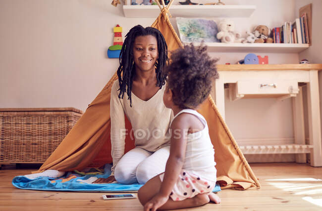 Madre e hija jugando en el piso del dormitorio - foto de stock