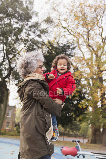 Бабушка с внуком на осенней детской площадке — стоковое фото