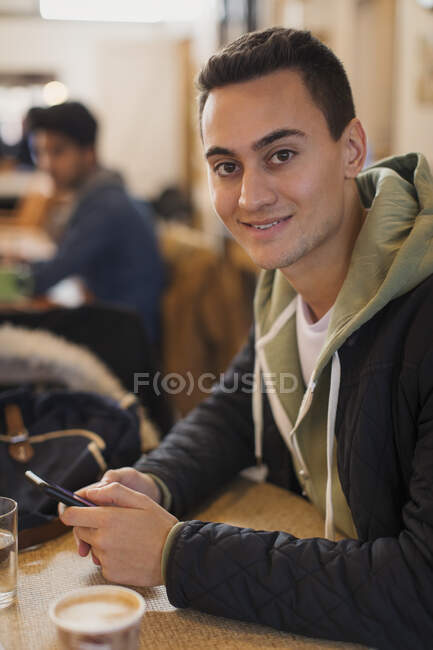 Портрет уверенный молодой человек с помощью смартфона в кафе — стоковое фото