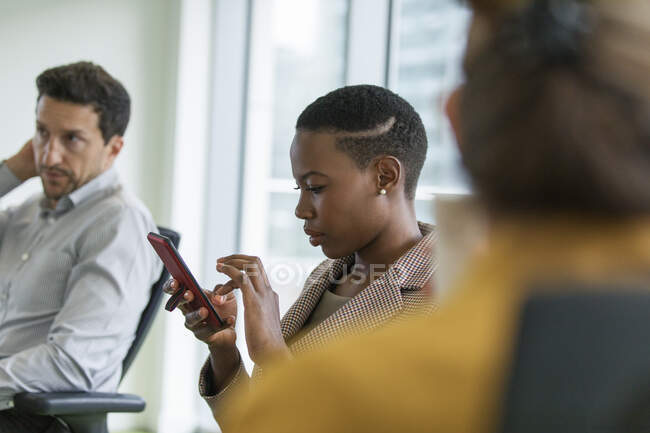 Donna d'affari che utilizza lo smart phone nella riunione della sala conferenze — Foto stock