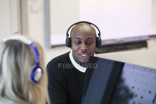Estudantes universitários comunitários com fones de ouvido usando computadores no laboratório de informática — Fotografia de Stock