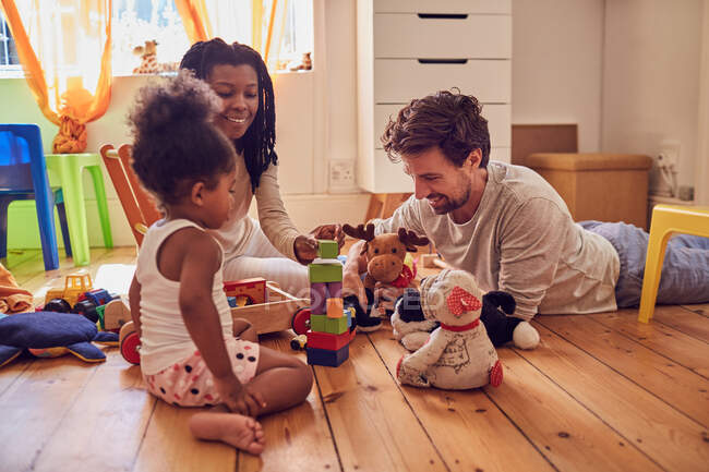 Jeune famille jouant avec des jouets sur le sol — Photo de stock