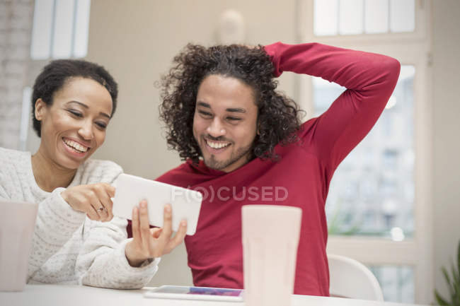 Щаслива пара використовує смартфон за столом — стокове фото