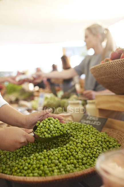 Frau schaufelt geschälte Erbsen auf Bauernmarkt — Stockfoto