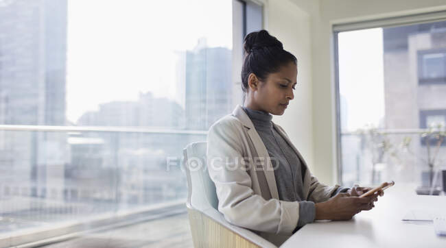Businesswoman using smart phone in urban conference room — Stock Photo