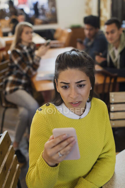Preoccupato giovane donna utilizzando smart phone in caffè — Foto stock