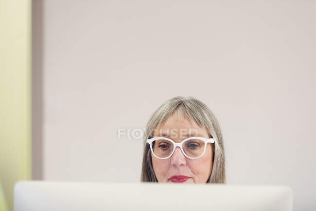 Сосредоточенная взрослая женщина в очках с помощью компьютера — стоковое фото