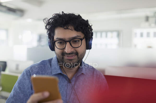Uomo d'affari che ascolta musica con cuffie e lettore mp3 — Foto stock