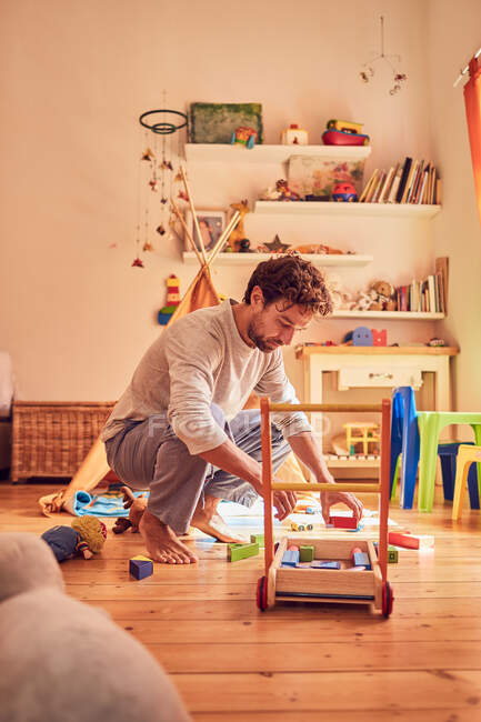 Father picking up toys in childs bedroom — Stock Photo
