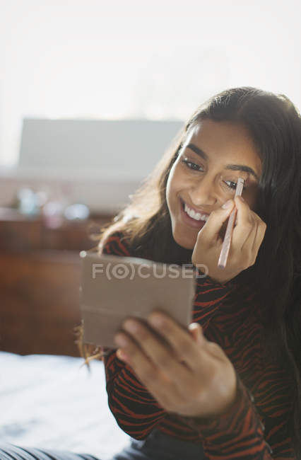 Sonriente adolescente aplicando maquillaje - foto de stock