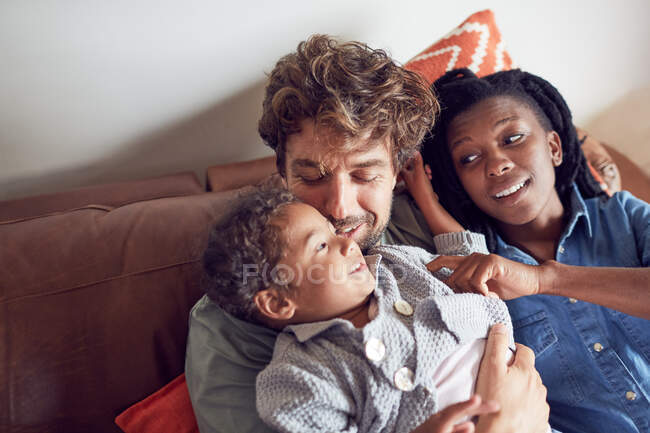 Affectionate young family cuddling on sofa — Stock Photo