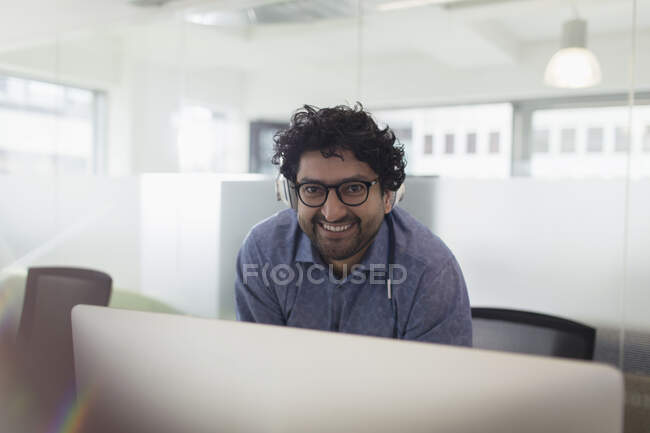 Retrato hombre de negocios confiado usando auriculares en la oficina - foto de stock