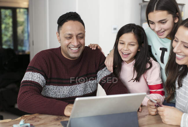 Familia feliz usando tableta digital en la mesa - foto de stock