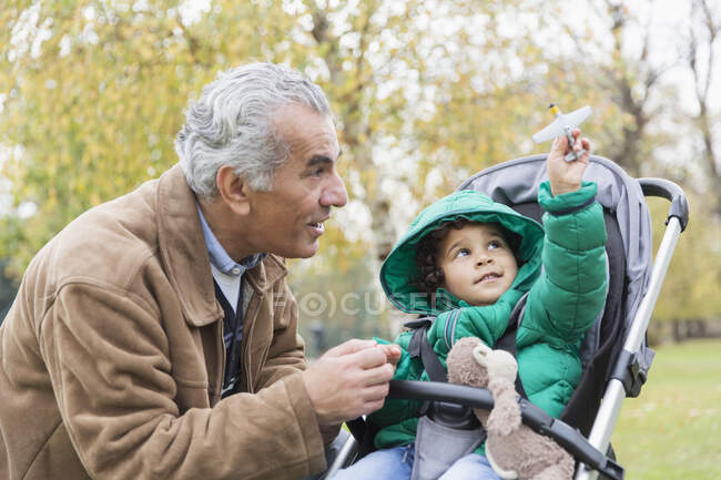 Abuelo con curioso nieto en cochecito - foto de stock