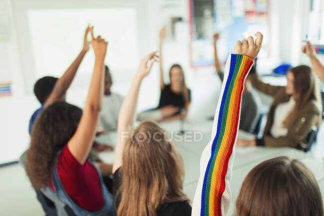 Estudantes do ensino médio com braços levantados, fazendo perguntas em sala de aula — Fotografia de Stock