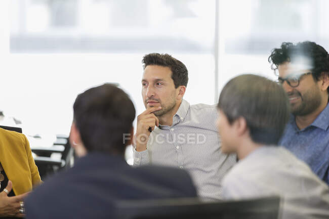 Konzentrierter Geschäftsmann hört in Besprechungsraum zu — Stockfoto