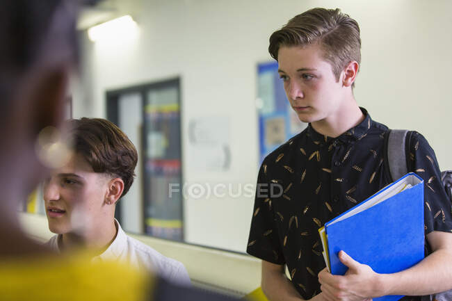 Орієнтований молодший школяр слухає друзів в коридорі — стокове фото