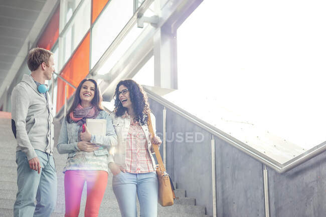 Young friends laughing, descending urban stairs — Stock Photo