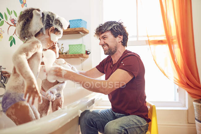Padre giocoso dando figlie bagno di bolla — Foto stock