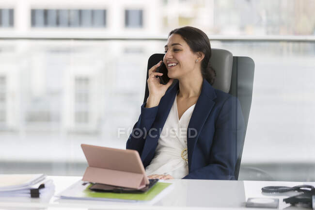 Усміхнена бізнес-жінка розмовляє по телефону в офісі — стокове фото
