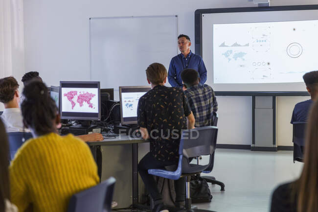 Alunos do ensino médio em computadores assistindo professor na tela de projeção em sala de aula — Fotografia de Stock