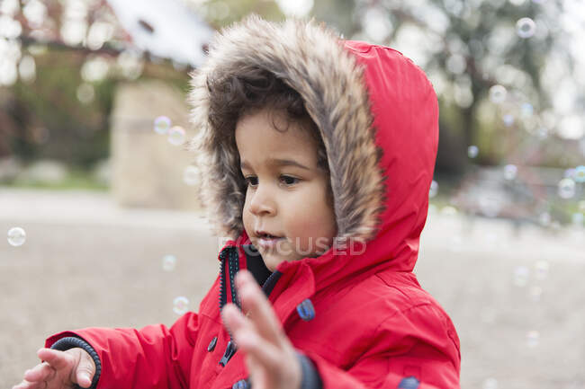 Милый, игривый мальчик играет с пузырьками — стоковое фото