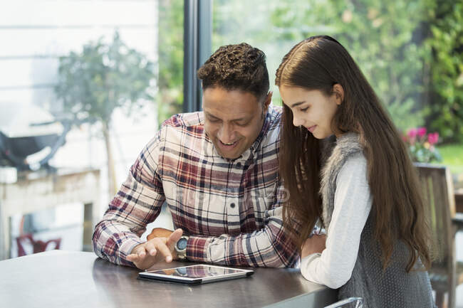 Father and daughter using digital tablet in kitchen — Stock Photo