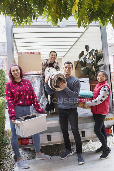Portrait happy friends unloading belongings from moving van — Stock Photo