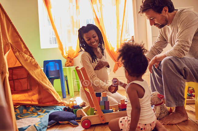 Familia joven embarazada jugando con juguetes - foto de stock