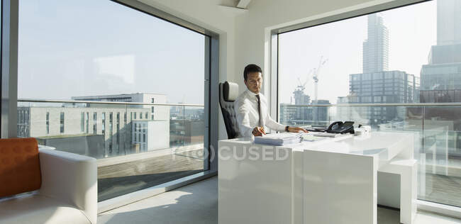 Geschäftsmann arbeitet in sonnigem, urbanem Büro — Stockfoto