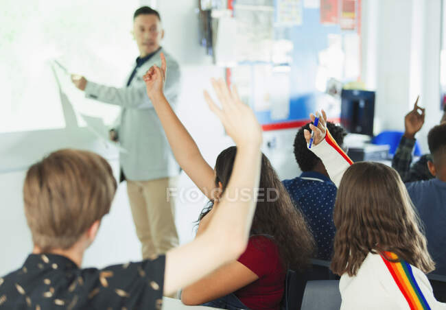 Estudantes do ensino médio com as mãos levantadas durante a aula — Fotografia de Stock