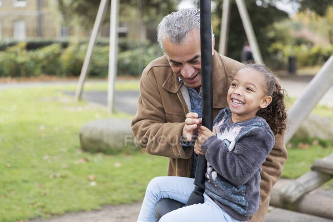 Счастливые дедушка и внучка играют на детской площадке — стоковое фото