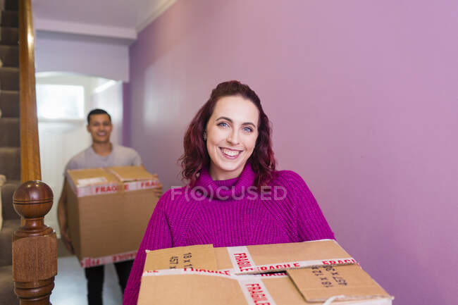 Retrato feliz pareja mudanza casa, llevando cajas de cartón en pasillo - foto de stock